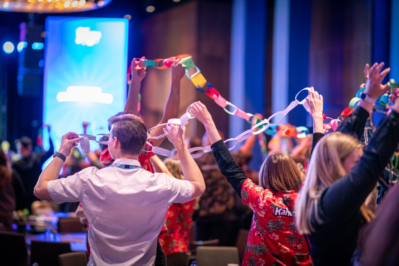A community ritual at a Kahoot! gathering, people linking paper chains overhead