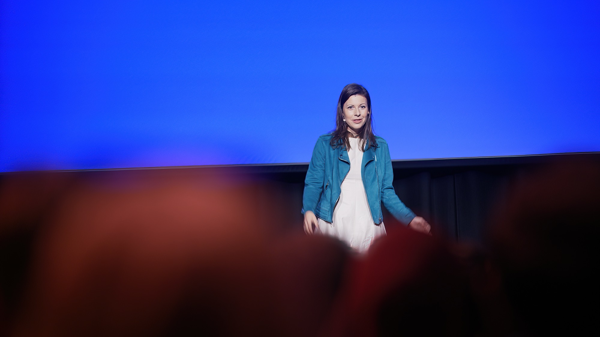 Irma delivering a keynote on a large stage to an audience
