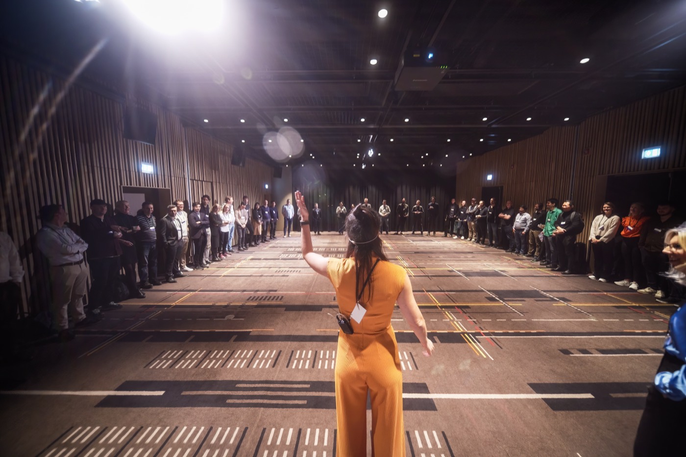 Irma leading a large standing circle of participants in a hall
